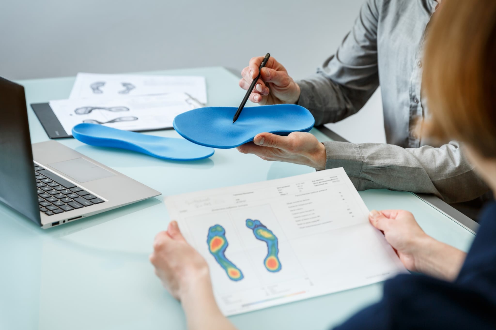 A clinician reviewing a custom orthotic and gait pressure report with a patient